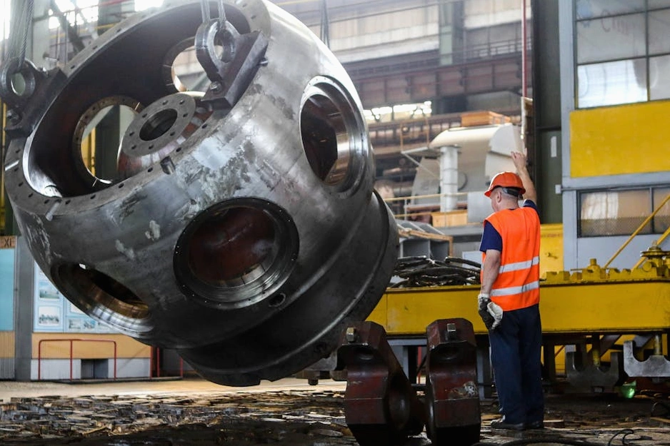 Ingegnere al lavoro su un macchinario industriale avanzato in un moderno stabilimento.